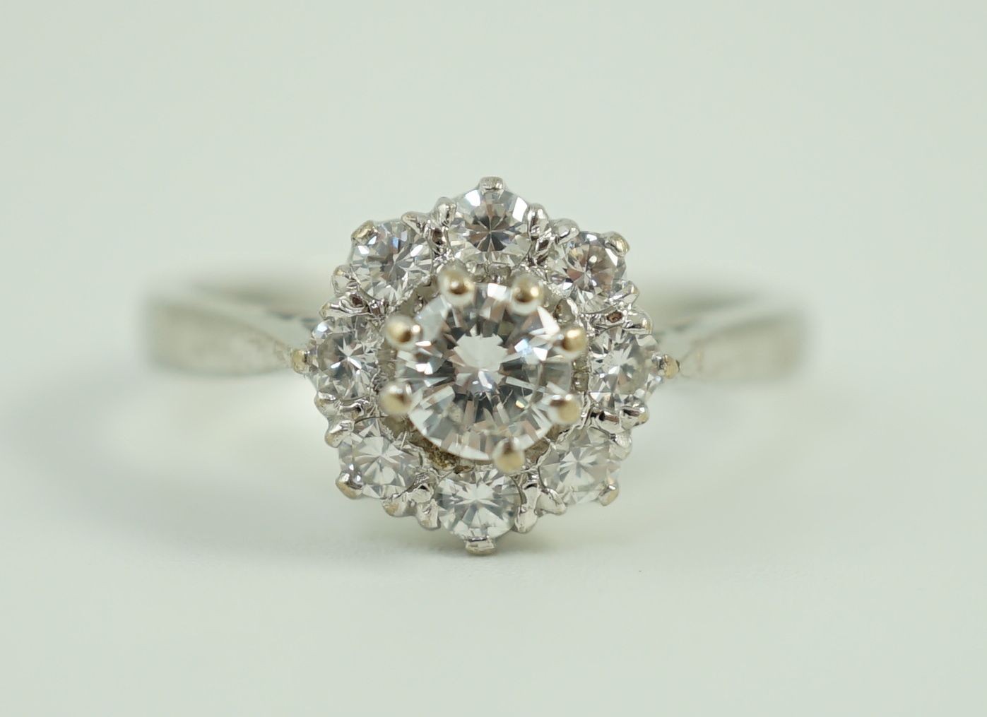 A modern 18ct white gold and nine stone diamond set flower head cluster ring